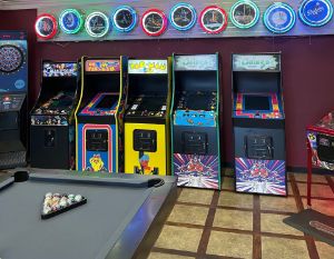 A line of arcade games behind a pool table.